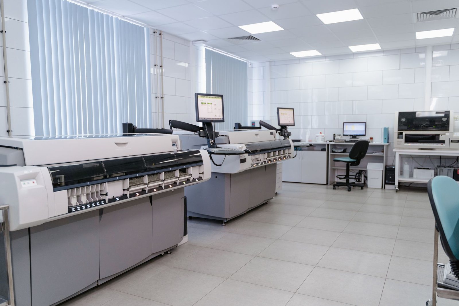 An empty clinical laboratory with automated analyzers, monitors and a workstation.